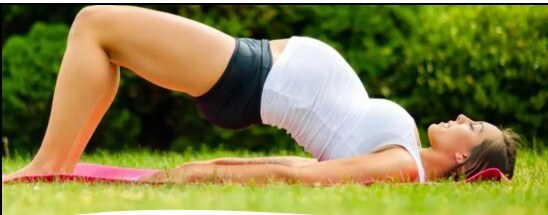 Pregnant woman performing bridge position exercise as alternative therapy